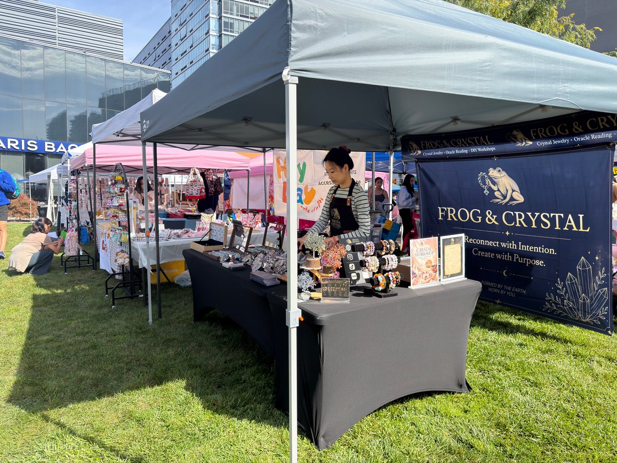 Frog & Crystal outdoor market booth with staff and a branded banner.